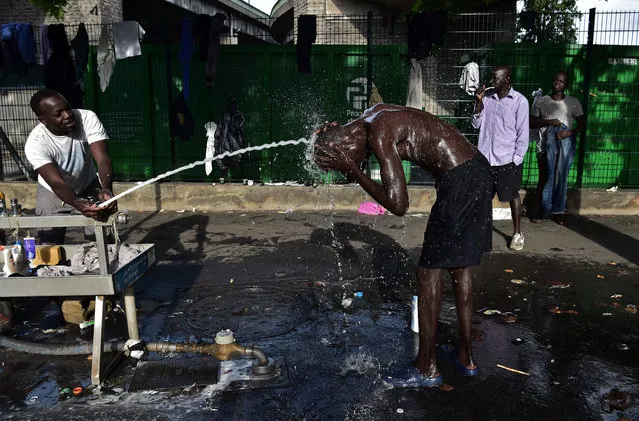 Migrants wash up on the pavement at Porte de la Chapelle in Paris on June 29, 2017. Some 1,200 people live on the street near the humanitarian centre for migrants, in the northern Parisian district according to the association France terre d' asile (FTDA), which has been mandated to help those who need assistance. (Photo by Christophe Archambault/AFP Photo)