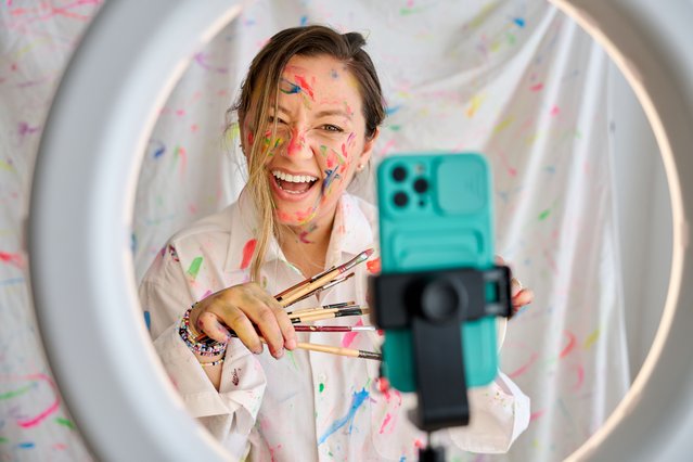 Female artist smiling while enjoying recording content for social media with mobile phone. Art, creativity and technology concept. (Photo by David Espejo/Getty Images)