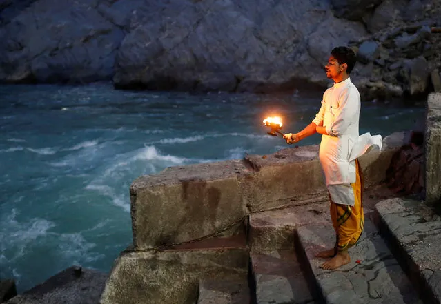 Lokesh Sharma, 19, a Hindu priest, performs evening prayers on the banks of the river Ganges in Devprayag, India, March 28, 2017. (Photo by Danish Siddiqui/Reuters)
