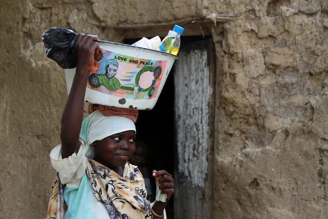 A girl balances a bowl with an old Nigerian naira note printed on, in Bichi village, on the outskirt of Nigeria's northern city of Kano July 25, 2012. (Photo by Akintunde Akinleye/Reuters)