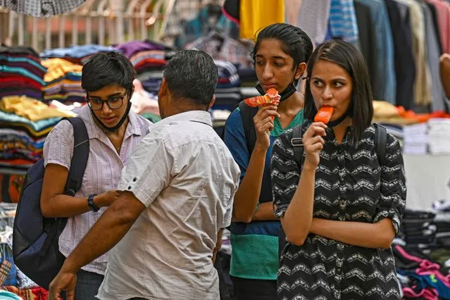 Girls have ice creams while shopping on a hot summer afternoon in New Delhi on April 28, 2022. (Photo by Prakash Singh/AFP Photo)