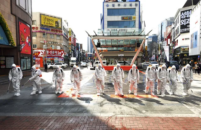 South Korean army soldiers wearing protective suits spray disinfectant to prevent the spread of the COVID-19 virus on a street in Daegu, South Korea, Thursday, February 27, 2020. As the worst-hit areas of Asia continued to struggle with a viral epidemic, with hundreds more cases reported Thursday in South Korea and China, worries about infection and containment spread across the globe. (Photo by Lee Moo-ryul/Newsis via AP Photo)