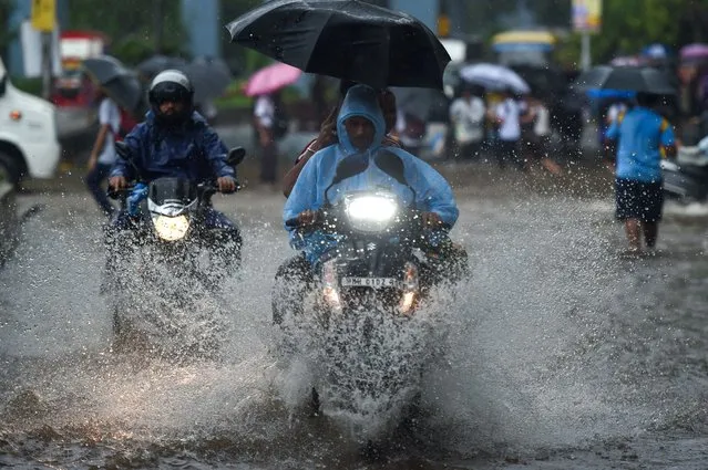 Vehicles drive through a flooded street during rain showers in Mumbai on July 5, 2022. (Photo by Punit Paranjpe/AFP Photo)