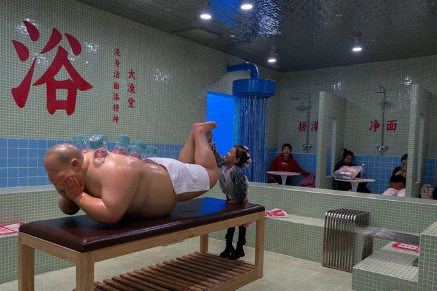 A child reaches out to touch a sculpture at a cafe with a bath house theme along the popular Wangfujing shopping street in Beijing, Friday, November 1, 2024. (Photo by Ng Han Guan/AP Photo)