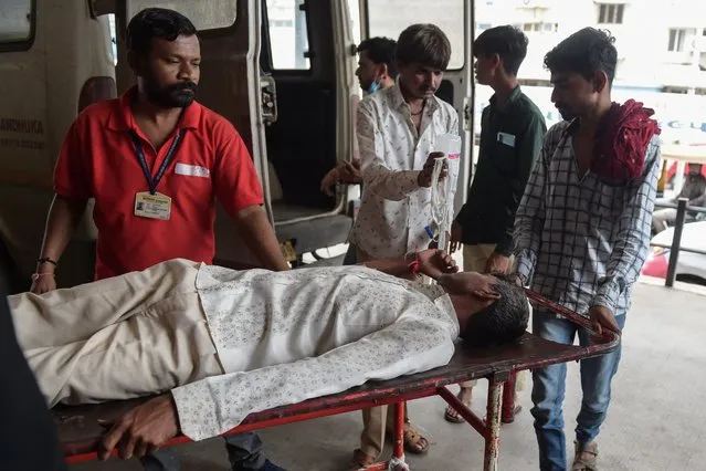 A man is shifted on a stretcher upon arriving in an ambulance at the Civil Hospital in Ahmedabad on July 26, 2022, after suffering health problems due to consuming bootleg liquor. (Photo by Sam Panthaky/AFP Photo)