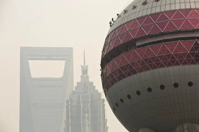 Workers clean the exterior of the Oriental Pearl TV Tower during a hazy day at Lujiazui financial district of Pudong in Shanghai, March 10, 2014. (Photo by Aly Song/Reuters)