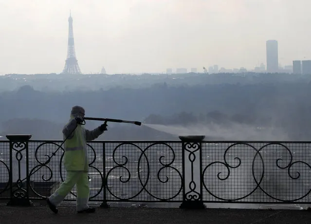 A worker wearing protective gears sprays disinfectant as a precautionary measure against COVID-19 during a nationwide confinement to counter the virus, in Suresnes, outside Paris, Tuesday, March 31, 2020. (Photo by Christophe Ena/AP Photo)