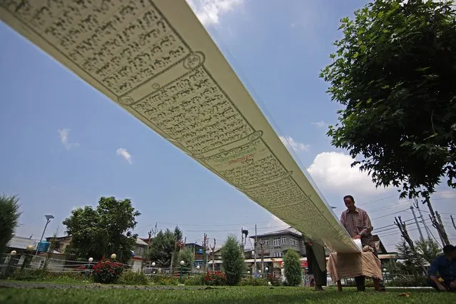 A visitor is seen during the display of the Holy Quran written by 27 year old, Mustafa-Ibn-Jameel on a 500 metre scroll ,Srinagar, Kashmir August 02, 2022. Mustafa who hails from Gurez Valley of north Kashmirâs Bandipora district has created a new world record by writing the Holy Quran on a 500-metre-long paper scroll and it took him seven months and the project was completed in Indian state of Delhi with a cost of Rs 2.5 lakh.The hand written copy of Quran has 450 pages and each page is 14.5 inches wide. (Photo by Faisal Khan/Anadolu Agency via Getty Images)