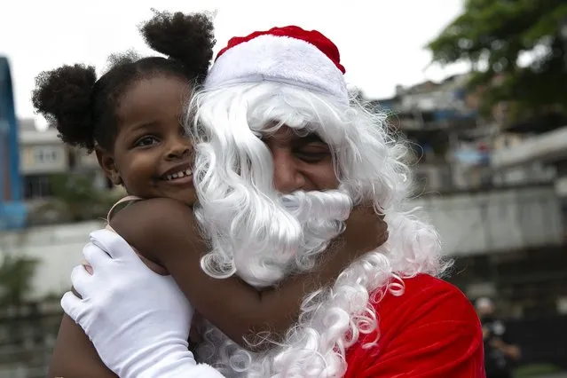 Leonan Pereira da Silva plays the part of Black Santa during a food donation event for the residents of the Vila Cruzeiro favela in Rio de Janeiro, Brazil, Thursday, December 23, 2021. Black Santa is presented to children as a Christmas character that better reflects their cultural reality, in a neighborhood where the great majority of residents are people of color. (Photo by Bruna Prado/AP Photo)