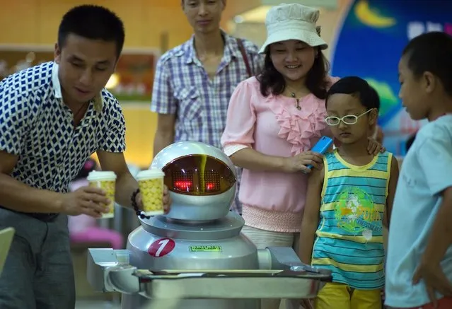 This photo taken on August 13, 2014, shows a robot serving a family the food they ordered. (Photo by Johannes Eisele/AFP Photo)
