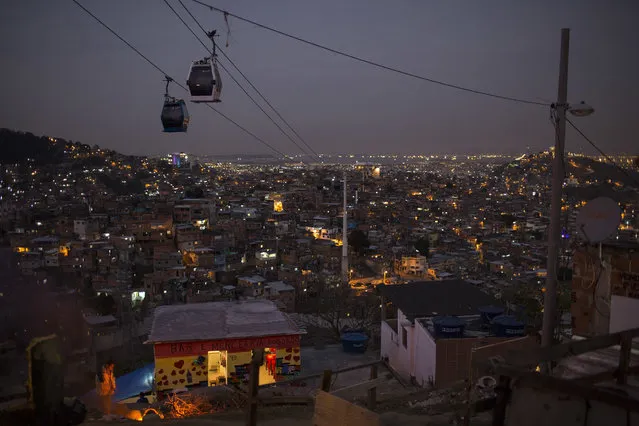 In this July 19, 2016 photo, cable cars transport commuters over the Complexo do Alemao, a sprawling cluster of slums in north Rio de Janeiro, Brazil. Just a short drive from upscale Rio districts like Ipanema and Copacabana, steep and narrow entryways lead to slums where poverty and gun violence dominate daily life for hundreds of thousands of residents. (Photo by Felipe Dana/AP Photo)
