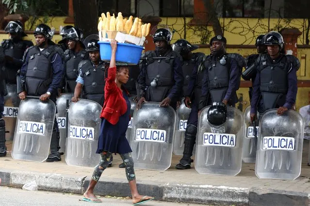 A woman walks past police officers as Angola's election commission says ruling MPLA party leads with 52% majority, after the general election close in Luanda, Angola on August 25, 2022. (Photo by Siphiwe Sibeko/Reuters)