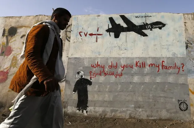 A man walks past a graffiti, denouncing strikes by U.S. drones in Yemen, painted on a wall in Sanaa, Yemen on November 13, 2014. (Photo by Khaled Abdullah/Reuters)