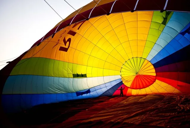 A crew member works to inflate a balloon before the international hot air balloons festival during in Park Timna, Israel, on October 3, 2012. (Photo by Ariel Schalit/Associated Press)
