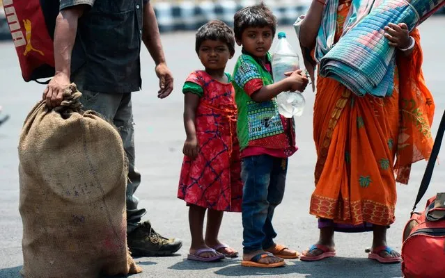 Children stand in a queue along with their parents outside Secunderabad Railway Station before boarding a train to return to their homes after the government eased restrictions as a preventive measure against the COVID-19 coronavirus, in Secunderabad on June 1, 2020. (Photo by Noah Seelam/AFP Photo)