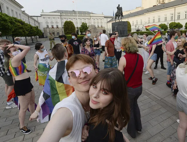 People, with Rainbow flags dance as they take part in a rainbow disco flashmob in front of the Presidential Palace in Warsaw, Poland, Thursday, June 11, 2020. Polish President Andrzej Duda signed a document called Family Card which is homophobic and discriminating in the perception of LGBT community. (Photo by Czarek Sokolowski/AP Photo)