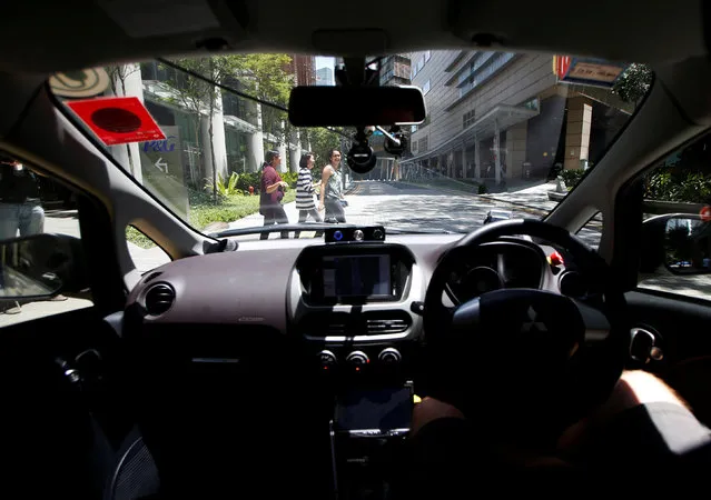 Pedestrians cross the road as a nuTonomy self-driving taxi undergoes its public trial in Singapore August 25, 2016. (Photo by Edgar Su/Reuters)