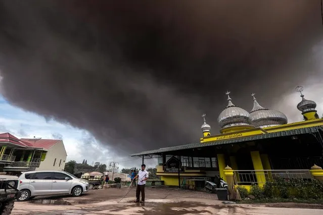 Mount Sinabung spews volcanic ashes as a villager cleans a mosque in Brastagi, Karo, North Sumatra, Indonesia, 26 August 2016. According to local media, the volcanic earthquake has continued to occur with eruptions of the ash cloud as 3.000 meters height. Indonesian military help vilagers to leave the red zone. (Photo by Y.T. Haryono/EPA)