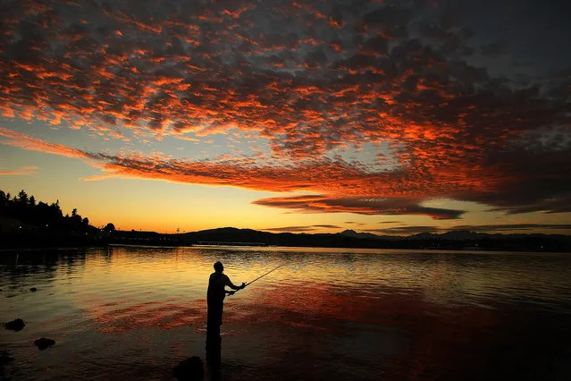 In this Friday, October 3, 2014 photo, Delmar Parris, of Port Orchard, Wash., casts his fishing line off Bay Street in Port Orchard during a fall sunset. (Photo by Larry Steagall/AP Photo/Kitsap Sun)