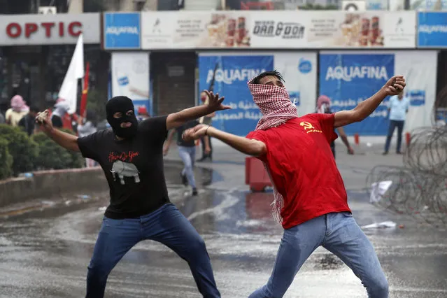 Hezbollah supporters and communist groups throw stones at riot police during a protest against U.S. interference in Lebanon's affairs, near the U.S. embassy in Aukar, northeast of Beirut, Lebanon, Friday, July 10, 2020. (Photo by Hussein Malla/AP Photo)
