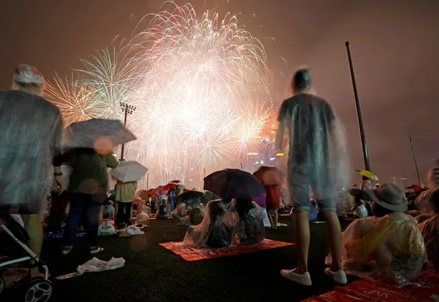 People watch fireworks in the rain ahead of the New Year at Marina Bay in Singapore on December 31, 2017. (Photo by Edgar Su/Reuters)