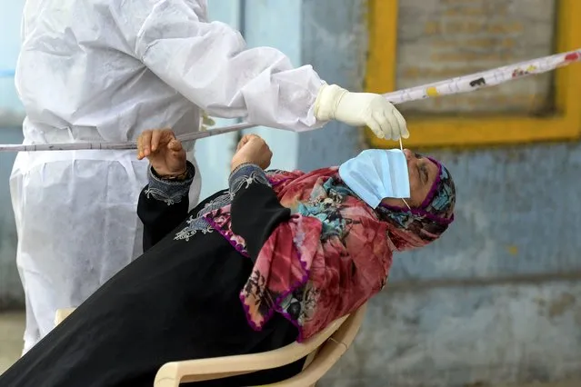 A health worker wearing Personal Protective Equipment (PPE) gear collects a swab sample from a woman at a free COVID-19 coronavirus testing centre in Hyderabad on August 26, 2020. India's confirmed coronavirus cases crossed the three million mark on August 23 with nearly 70,000 new infections, as the disease continues to surge in the world's second most-populous nation. (Photo by Noah Seelam/AFP Photo)