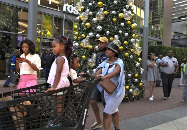 Shoppers pass a Christmas tree at the entrance to the Rosebank Shopping Mall in Johannesburg Saturday, December 23, 2022. South Africa's Christmas 2022 is a start/stop affair because the country's daily power cuts are hitting just about every aspect of the holiday with businesses and families coping with rolling outages of electricity lasting from seven to 10 hours per day. (Photo by Denis Farrell/AP Photo)