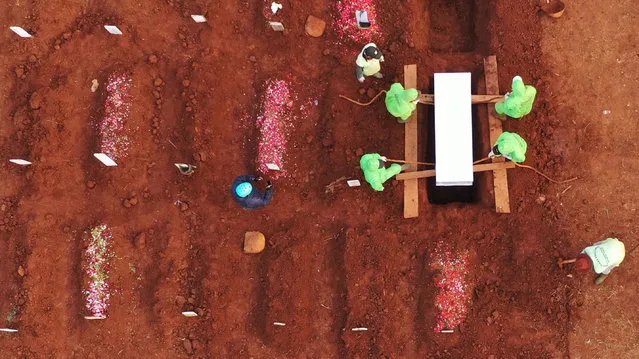 This aerial picture taken on August 10, 2020 shows gravediggers burying victims of the COVID-19 coronavirus at the Pondok Ranggon cemetery in Jakarta. The country of nearly 270 million is among the worst hit in Asia by the pandemic, with cases in all its 34 provinces, including the remote Maluku island and easternmost Papua. (Photo by Adek Berry/AFP Photo)