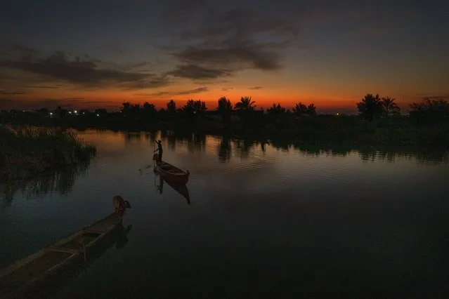 The sun sets as an Iraqi fishermen heads out on his boat in the Chibayish marshes of southern Iraq, in Dhi Qar, Iraq, Saturday, November 19, 2022.. (Photo by Anmar Khalil/AP Photo)