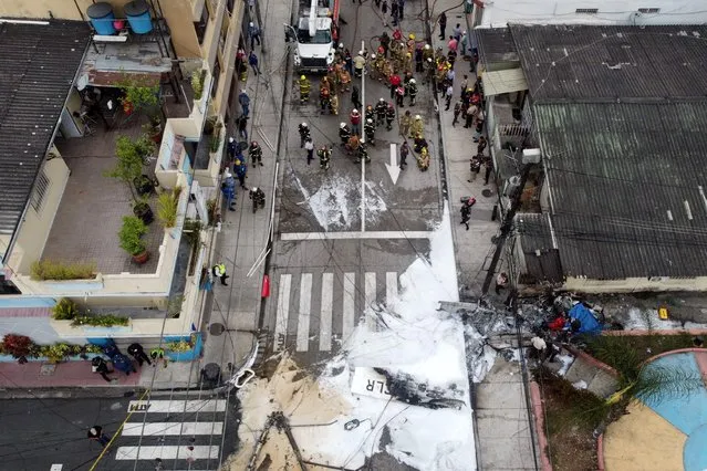 In this aerial view firefighters, police and rescuers work at the site where a light aircraft crashed leaving two people dead in Guayaquil, Ecuador, on October 18, 2022. A small plane crashed on Tuesday in the park of a populated neighborhood of Guayaquil, killing two people on board and injuring the pilot, said the mayor of the Ecuadorian port, Cynthia Viteri. (Photo by Marcos Pin/AFP Photo)