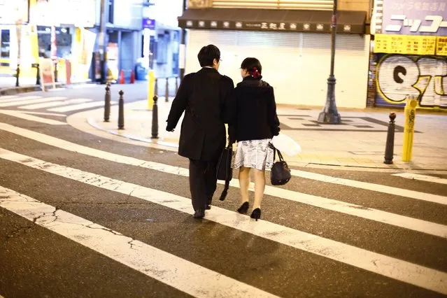 A couple cross a street in the amusement district of Osaka, western Japan November 19, 2014. (Photo by Thomas Peter/Reuters)