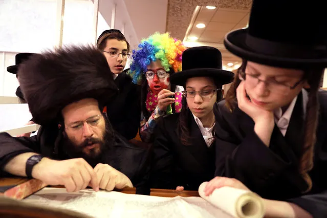 A boy dressed up in a Purim costume looks on as ultra Orthodox Jews take part in the reading from the Book of Esther, a ceremony performed on the Jewish holiday of Purim, in Jerusalem, March 1, 2018. (Photo by Ammar Awad/Reuters)