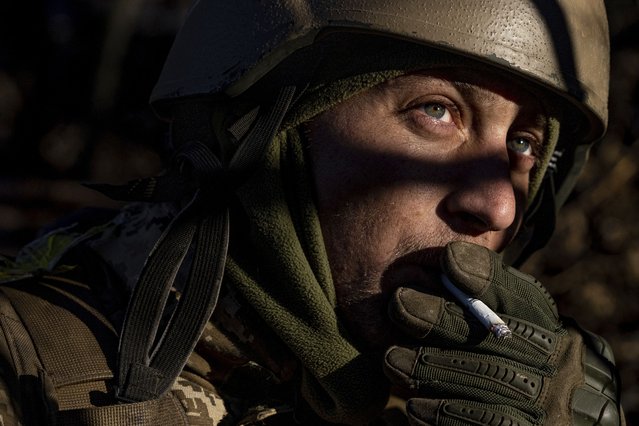 A Ukrainian serviceman smokes a cigarette at his position at the frontline near Bakhmut, Donetsk region, Ukraine, Wednesday, January 11, 2023. (Photo by Evgeniy Maloletka/AP Photo)