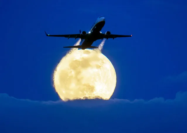 An aircraft passes the rising full moon that breaks through the clouds at the airport in Frankfurt, Germany, Monday, March 9, 2020. (Photo by Michael Probst/AP Photo)