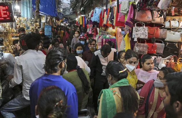 People wearing masks as a precaution against the coronavirus shop at a market on the eve of Karwa Chauth Hindu festival in Jammu, India, Tuesday, November 3, 2020. Married Hindu women observe a day long fast for the health and long life of their husbands on this day. Karwa Chauth will be celebrated on November 4. (Photo by Channi Anand/AP Photo)