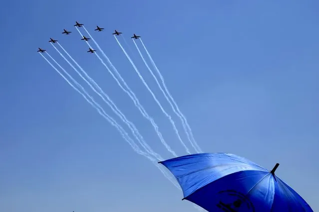 Visitors watch Indian Air Force's aerobatic team Suryakiran perform maneuvers on the second day of the Aero India 2023 at Yelahanka air base in Bengaluru, India, Tuesday, February 14, 2023. Aero India is a biennial event with flying demonstrations by stunt teams and militaries and commercial pavilions where aviation companies display their products and technology. (Photo by Aijaz Rahi/AP Photo)