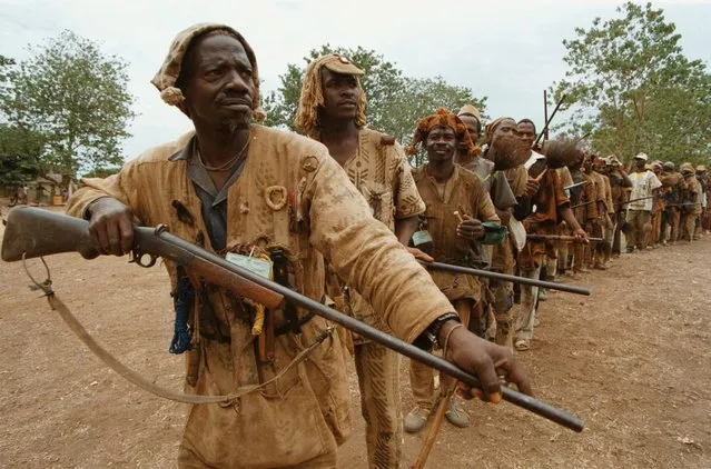 A group of “dozos”, hunters with powers, in the Malinke language, parade in a circle in the Ivory Coast village of Madinani April 3, 1996. A thousand hunter/singers gathered at a government environmental conference to discuss saving the Ivorian rain forest and to lobby for the right to bear arms, a part of their culture and livelihood outlawed since 1984. (Photo by David Guttenfelder/AP Photo)