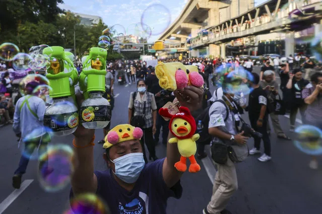 A man holds up bubble blowers and merchandise designed as yellow ducks, which have become good-humored symbols of resistance during anti-government rallies, Friday, November 27, 2020 in Bangkok, Thailand. (Photo by WasonWanichakorn/AP Photo)
