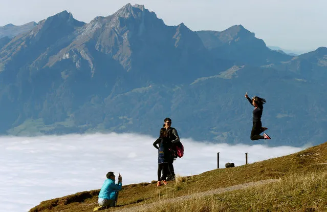 Mount Pilatus is seen behind the fog as tourists from China take a picture on the peak of Mount Rigi, Switzerland at 1,797 m (5,896 ft) above sea level October 16, 2016. (Photo by Arnd Wiegmann/Reuters)
