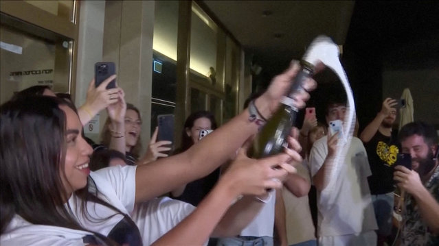Natali Zangauker, sister of hostage Matan Zangauker, pops a bottle of champagne while reacting to news that Israel and Hamas have agreed to the first phase of a peace plan for Gaza, at Hostages Square in Tel Aviv, Israel, on October 9, 2025. (Photo by Reuters TV)