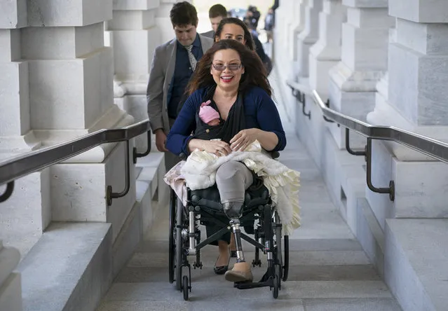 Sen. Tammy Duckworth, D-Ill., arrives at the Capitol for a close vote with her new daughter, Maile, bundled against the wind, in Washington, Thursday, April 19, 2018. In an historic change in Senate rules, the lawmakers decided to allow babies of members on the floor during votes. (Photo by J. Scott Applewhite/AP Photo)