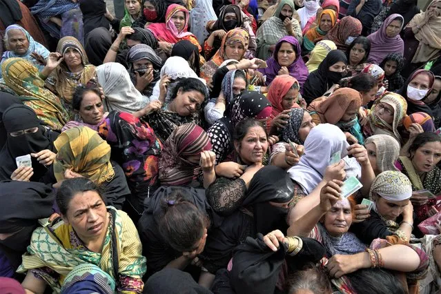 Women jostle to get a free sack of wheat flour at a distributing point, in Lahore, Pakistan, Monday, March 20, 2023. Pakistan's Prime Minister Shahbaz Sharif will provide free flour to deserving and poor families during the Muslim's holy month of Ramadan due to high inflation in the country. (Photo by K.M. Chaudary/AP Photo)