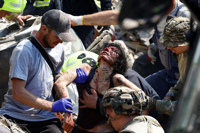 Rescuers carry an injured woman rescued from the debris, at a site of a Russian missile strike, amid Russia's attack on Ukraine, in Kyiv, Ukraine on July 8, 2024. (Photo by Valentyn Ogirenko/Reuters)