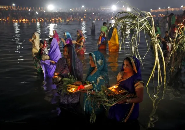 Hindu women offer prayers as they wait for the rising sun while standing in the waters of a lake during the Hindu religious festival of Chatt Puja in Chandigarh, India, November 18, 2015. During this festival, Hindu women fast for the whole day for the betterment of their families and society. (Photo by Ajay Verma/Reuters)