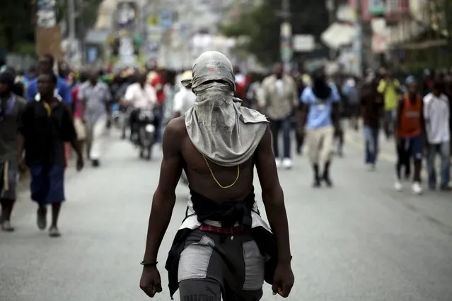 A protestor covering his head with a t-shirt marches during a demonstration against the results of the presidential elections in Port-au-Prince, Haiti, November 26, 2015. (Photo by Andres Martinez Casares/Reuters)