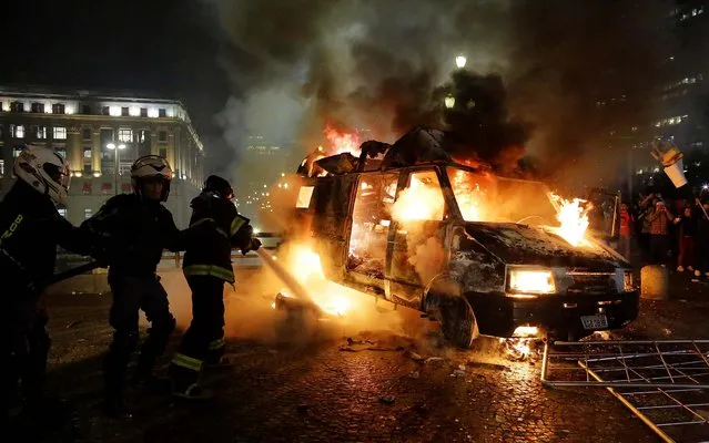 Firefighters work to put out a burning vehicle set on fire by protesters in front of City Hall in Sao Paulo, Brazil, on June 18, 2013. Some of the biggest demonstrations since the end of Brazil's 1964-85 dictatorship have broken out across this continent-sized country, uniting multitudes frustrated by poor transportation, health services, education and security despite a heavy tax burden. (Photo by Nelson Antoine/Associated Press)