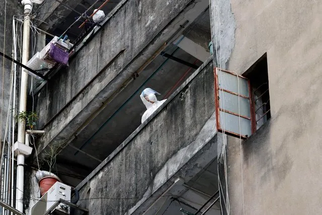 A medical worker in a protective suit is seen inside one of the buildings at a residential area at Jordan where tens of thousands of its residents will be placed in a lockdown to contain a new outbreak of the coronavirus disease (COVID-19), in Hong Kong, China on January 22, 2021. (Photo by Tyrone Siu/Reuters)
