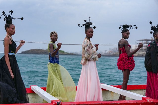 Models wear creations on a traditional fishing boat during Dakar Fashion Week in Senegal, Saturday, December 6, 2025. (Photo by Misper Apawu/AP Photo)