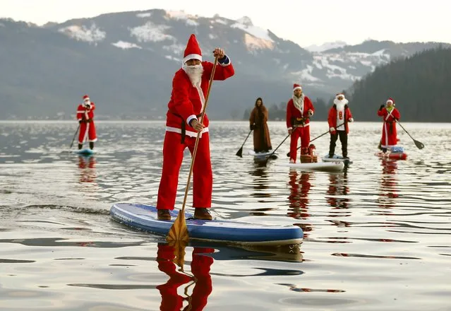 People dressed as Santa Claus pose on their stand-up paddles as they cross Lake Aegerisee near Oberaegeri, Switzerland December 5, 2015. (Photo by Arnd Wiegmann/Reuters)
