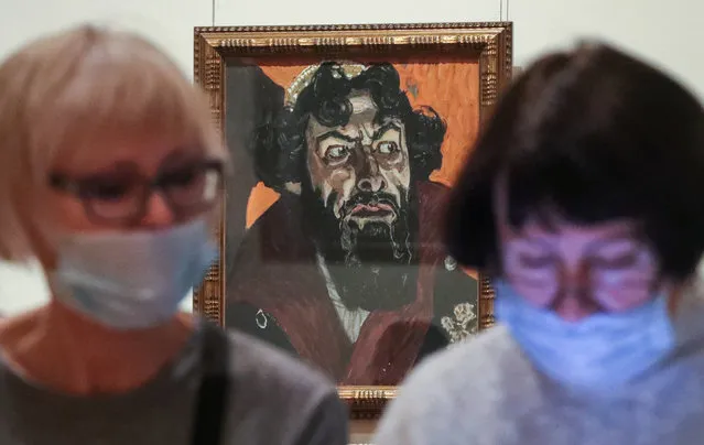 Visitors are seen during a preview of the exhibition titled Alexander Benoit and the World of Art Association at Tretyakov Gallery in Moscow, Russia on January 28, 2021. Seen behind is Alexander Golovin's Portrait of Feodor Chaliapin as Boris Godunov (1912). The exhibition, part of a series of changing exhibitions titled the Artist and the Time, features some 200 illustrations, book design elements, and postcards by prominent artists of the Mir Iskusstva (World of Art) Association, including Alexander Benoit, Lev Bakst, Mstislav Dobuzhinsky, Boris Kustodiev and others. (Photo by Vyacheslav Prokofyev/TASS via Getty Images)